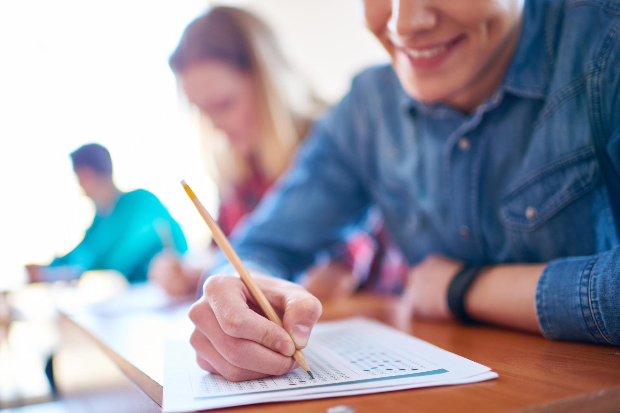 A young man taking a written exam in a classrom.